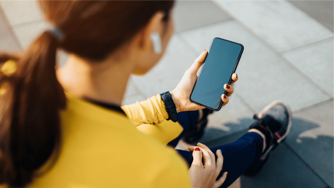person using a mobile phone with earbuds in