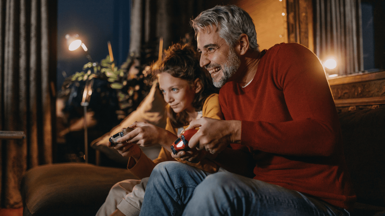 Parent and child on couch playing a video game. 